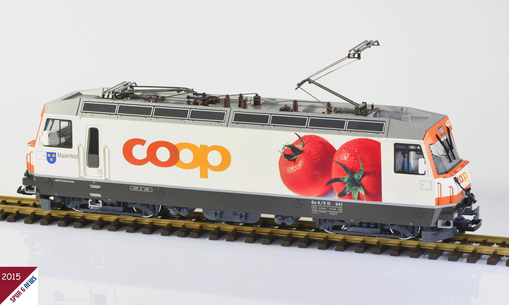 Auf dem Gleis macht das Modell von LGB, Ge 4/4 III - 641-  Maienfeld - 641 -  coop Tomate mit der LGB Artikel Nummer 21427 ein geflliges Bild mit stimmigen Farben. Hier ist der Lokfhrer im Stand I eingebaut. Dieser wird bei der nchsten Lokkontrolle gegen einen anderen aus dem Zubehrhandel getauscht. Lokstand II befindet sich auf diesem Bild auf der linken Seite. Sehr schn auch die Frontfarbe in Orange - Anlehnung an das coop Zeichen. 