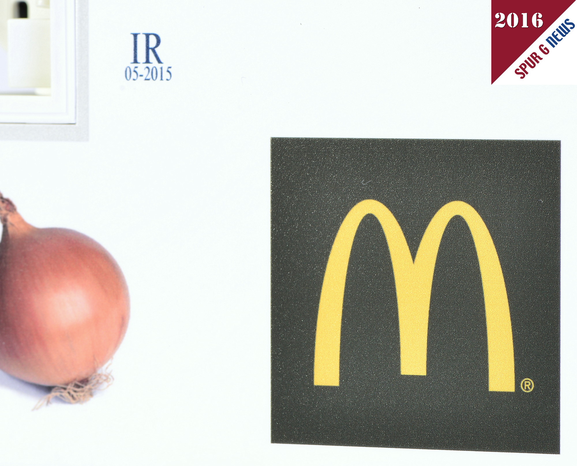 Beim Fotografieren und am PC fllt es auf: Die Zwiebel auf der linken Bildhlfte ist durch die Struktur der Schale und der feinen Wurzeln nicht so "rauh" als das MC Donalds Emblem. Leider kann auf dem Bildschirm die Oberflche noch nicht greibar erfhlt werden. Das dunkelbraune ins schwarz gehende Quadrat ist durch die Farbpigmentierung rauher als die Schale der Zwiebel. Nur die Lichtreflektion der Blitzlampen macht den Digitaldruck hier im Schwarzbereich sichtbar. 