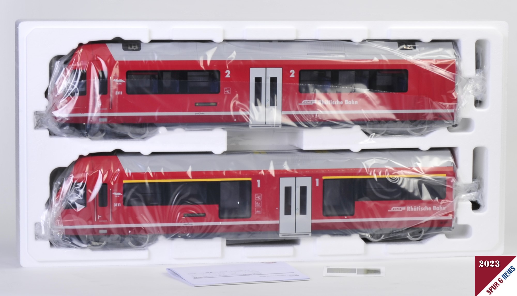 Die Verpackung - rote Schachtel - wurde entfernt. Der Deckel der Styroporbox abgehoben und der Steuerwagen (unten) und der Triebkopf (oben) sind in der Kunststoffumhüllung zu sehen.