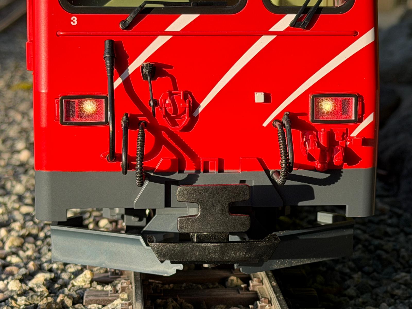 Teilansicht der Front der HGe 4/4 II MGB mit Kupplungen, Schluchen, Steckdosen und dem Puffer. 