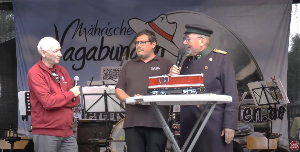 Bildunterschrift v.l.n.r: Wolfrad Bächle, Daniel Kahler und Alfred Simm bei der Präsentation der neuen LGB Lok auf der 19. Historik Mobil in Bertsdorf. Verschiedene historische Zuggarnituren waren bei der Zittauer Schmalspurbahn an diesem Wochenende im Dauereinsatz. Bereits am Freitagabend gab es einen ersten Vorgeschmack mit Abendfahrten bis 23 Uhr. I K 54 und IV K 145 fuhren den Sachsenzug. Im Aussichtswagenzug spielte Livemusik. Und der neue LGB Produktmanager Daniel Kahler hatte einen Überraschung dabei!