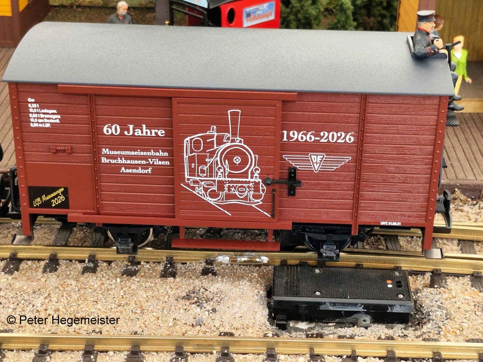 Bild unten: Der LGB Museumswagen 2026 zum Jubil�um 60 Jahre DEV auf  der Modellbahnanalge des Clubs der LGB-Freunde Niederrhein. Auch Bremser "Guido" aus der Figurenfabrikation "figurendesign Bauer" hat seinen Platz eingenommen. 