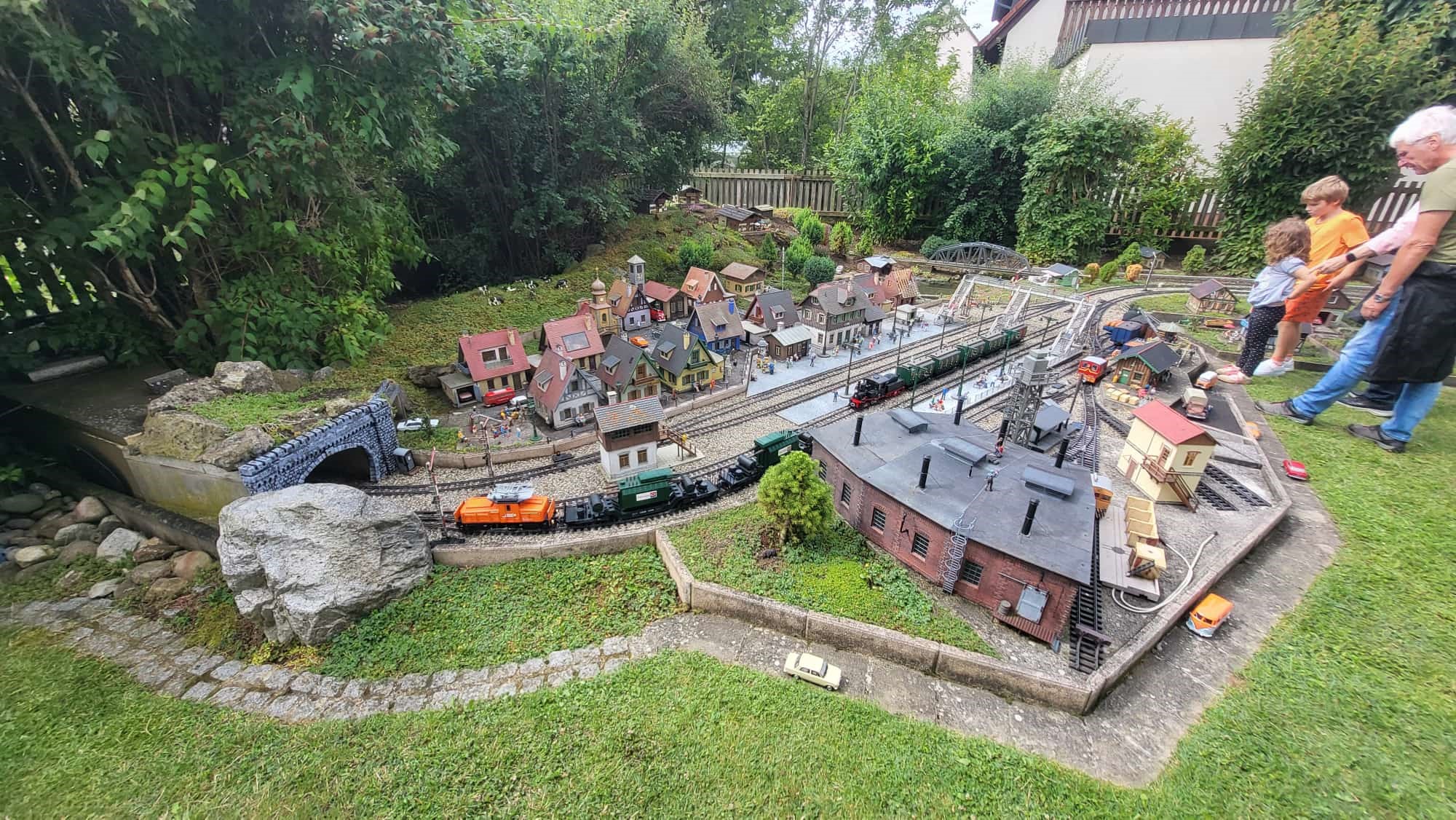 Der dritte Teil der Anlage zeigt bi Martin die Stadt mit der tollen Brcke ber die Bahngleise. Im Vordergrund ist der Ringlokschuppen mit Wasserwerk zu erkennen. Hier fahren nicht nur die Elektrolokomotiven sondern auch mit Dampflokomotiven bespannte Zge. Viele Kinder mit Eltern oder Groeltern haben einen bleibenden Eindruck von einer perfekten Gartenbahnanlage mitgenommen. 