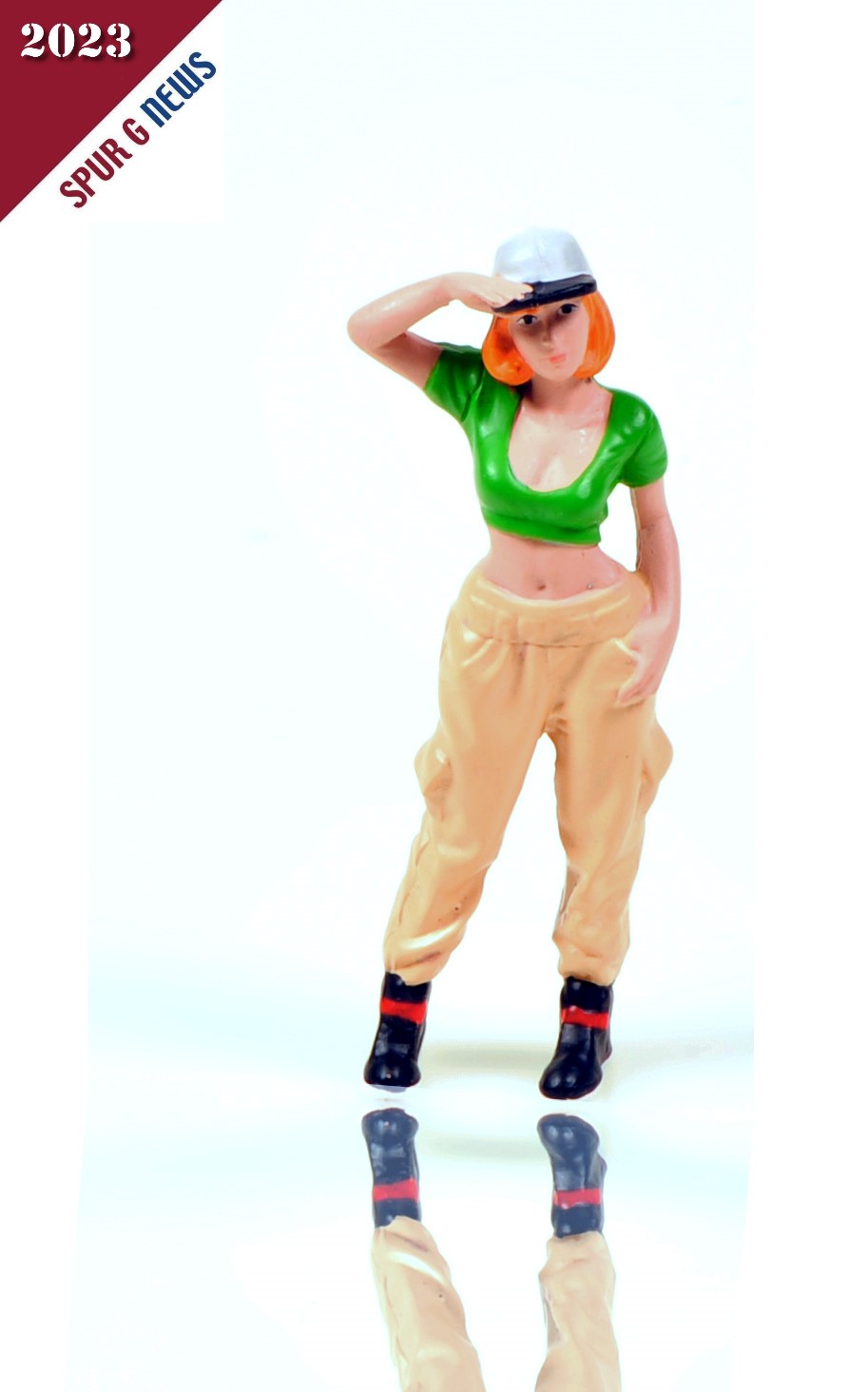 American Diorama - Art. Nr. 24101, HipHop Girl "Alexandra", Die Hand an der weißen Mütze, die die roten Haare schützt, steht das HipHop Girl lässig mit einem Finger in der Tasche da. Moderne, beige Jogginghose, bauchfreies grünes Top und schwarze Stiefelchen mit roten Streifen sind der Stil dieser Figur.