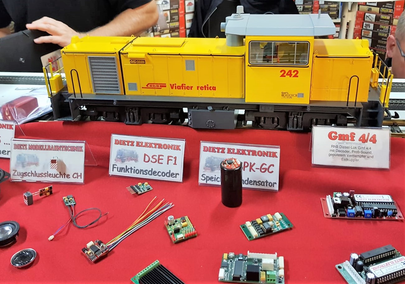 Eine Gmf 4/4 der Rhtischen Bahn ist derzeit im Angebot von Dietz Elektronik noch  zu kaufen. Auf dem linken Bild sind vor der Lokomotive verschiedene Zurstbausteine oder Elektronik fr den Zugbetrieb im Original ausgestellt worden. Fr die RhB Fahrer ist z.B. die blinkende Schluleuchte an den Zgen eines der Highlights fr den Modellbahnbetrieb. Aber auch die unterschiedlichen Decoder oder Susi Bausteine wurden gezeigt und erklrt. 