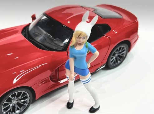 American Diorama - Art. Nr. 24303 - Cosplay Girl # 3, Kusohu,Mit einer Art Osterhasenmütze auf den blonden Haaren steht das Cosplay Girl mit hohen Strümpfen in Ihrem blauen knappen Rock und dem blauen Shirt aufrecht. Auf dem Rücken hat sie einen grünen kleinen Rucksack. Die langen Strümpfe haben oben zwei blaue Streifen. Das Auto ist wie immer nicht im Lieferumfang enthalten.