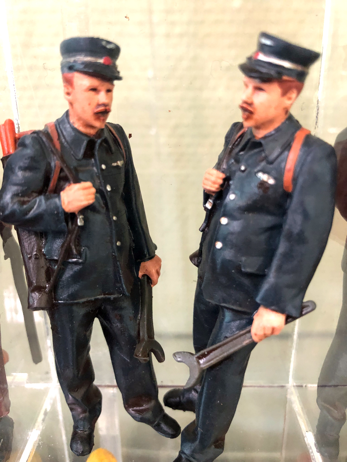 Links im Bild ist ein Schweizer Bahnbeamter zu sehen. Der große Gabelschlüssel ist für die Reparatur an einer Lok vorgesehen. Aus dieser Serie der Schweizer Bahnbediensteten gibt es noch mehr Darstellungen.