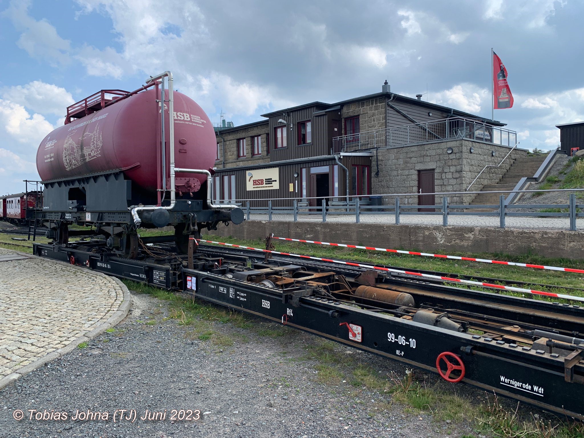 Die beiden Rollwagen der HSB vorne mit dem HSB Löschwasserwagen beladen: 99-50-54 und ohne Beladung 99-06-10. Blick zum Bahnhof Brocken in dem auch die Gaststätte untergebracht ist.