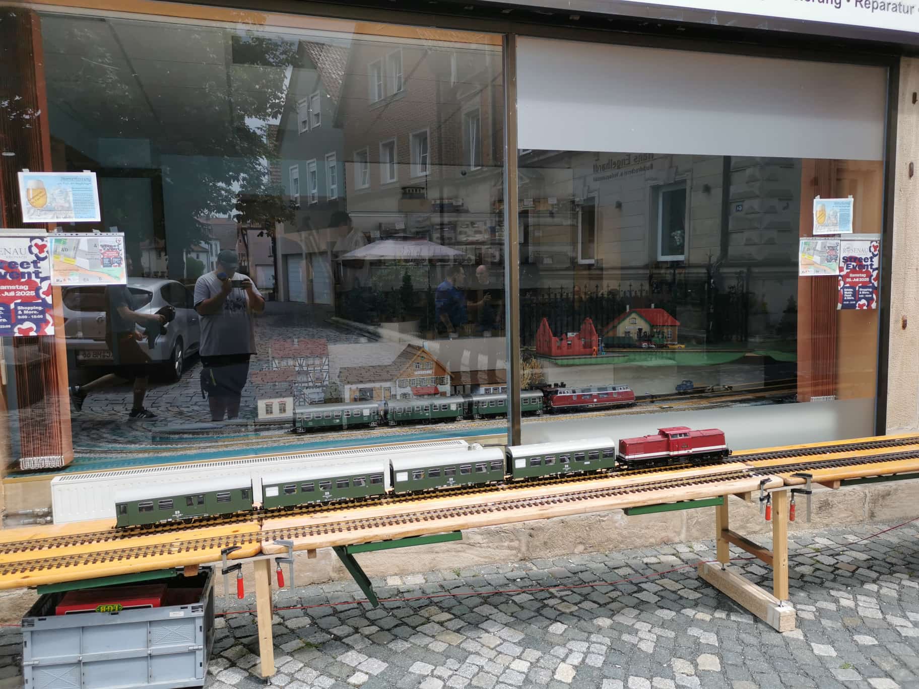 Vor dem Modellbaustudio Raab in der Rosenau wurde auf Holzböcken der Anfang zum rund 100 Meter langen Rundkurs in und vor das Studio der Höhenausgleich geschaffen. Hier eine V100 mit vier Personenwagen am Haken.