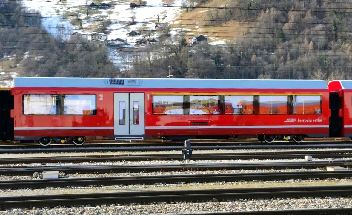 1./2. Klasse Wagen mit 5 groen Fenstern in der ersten Klasse und  zwei Fenster fr die 2. Klasse. Doppeltren mit einer Breite von 1.400 mm und Niederflureinstieg ist auch hier vorhanden. Die Erstklass-Fahrgastrume (im Bild die rechten 5 Fenster) sind mit Komfortsthlen, integrierten Bedienpanels fr Lesespots und einer Rollosteuerung ausgestattet. Die RhB schreibt auch "Echt Erst-Klassbestuhlung in Anordnung 1+2". Dieser Wagen wird AB 57201 bis AB 57206 beschriftet. 29 Pltze der 1. Klasse, 16 Pltze der 2. Klasse, ein VELO und Kinderwagen passen in den Wagon. WC ist hier keines vorgesehen. 