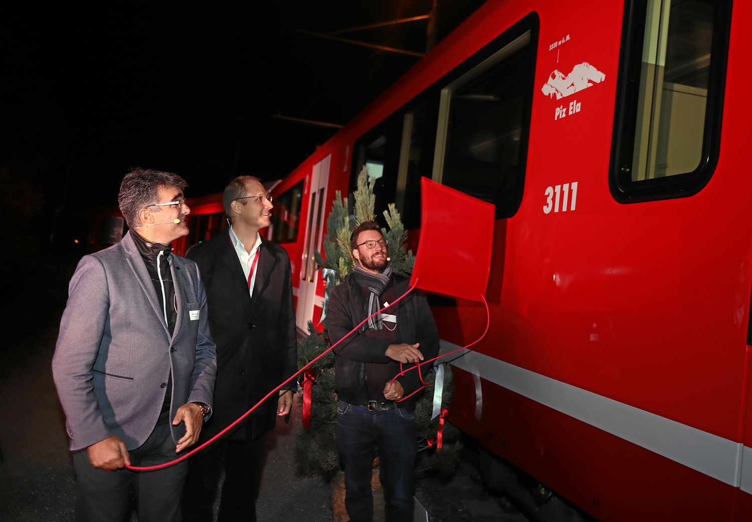 Foto: RhB -  Rhtische Bahn: Zugtaufe mit Marcus Caduff (links i. Bild), Luzi C. Schutz (rechts i. Bild) und Dr. Renato Fasciati (Mitte). 