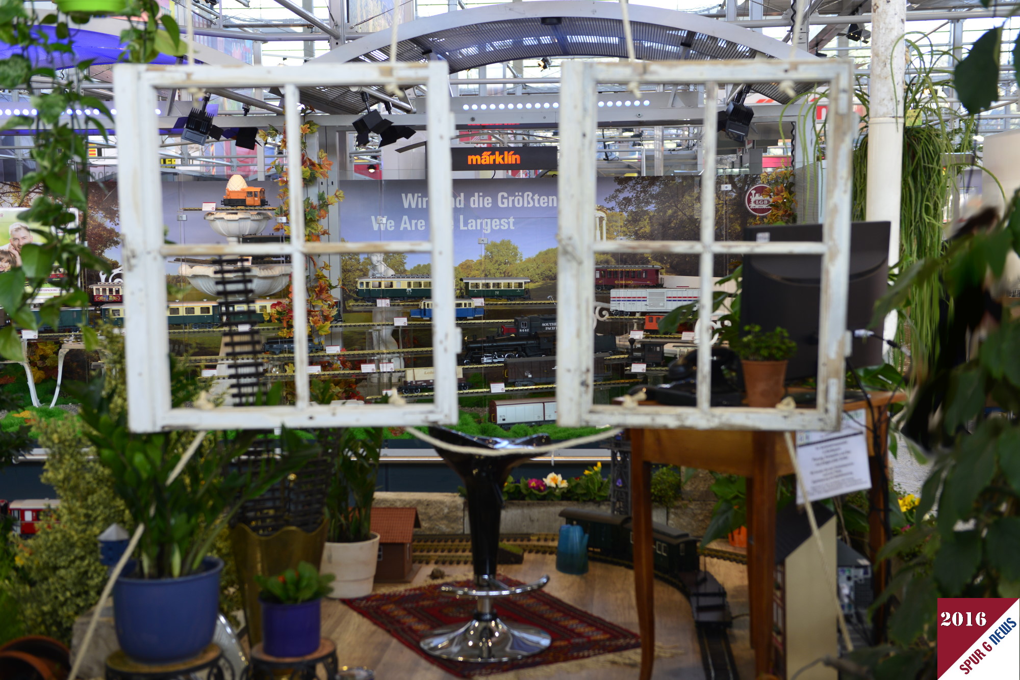 Die Showanlage auf der Spielwarenmesse 2016 von LGB wurde wieder durch das GartenbahnCenter Nürnberg erstellt. Es wird gezeigt, dass nicht nur im Garten die LGB Ihre Runden im Oval zuverlässig dreht, sondern auch im Arbeitszimmer unterm Sekretär vorbei an den Topfpflanzen wieder in den Garten fährt. Im Regenschirmständer sind die Ersatzgleise eingestellt und ein Reliefhaus von POLA sowie die Lagerhalle Waldau lassen Stadt- und Bahnhofsatmosphäre aufkommen. Der Blick auf die Neuheiten durch die beiden Sprossenfenster rundet die Ansicht und Aussicht der Anlage hervorragend ab.