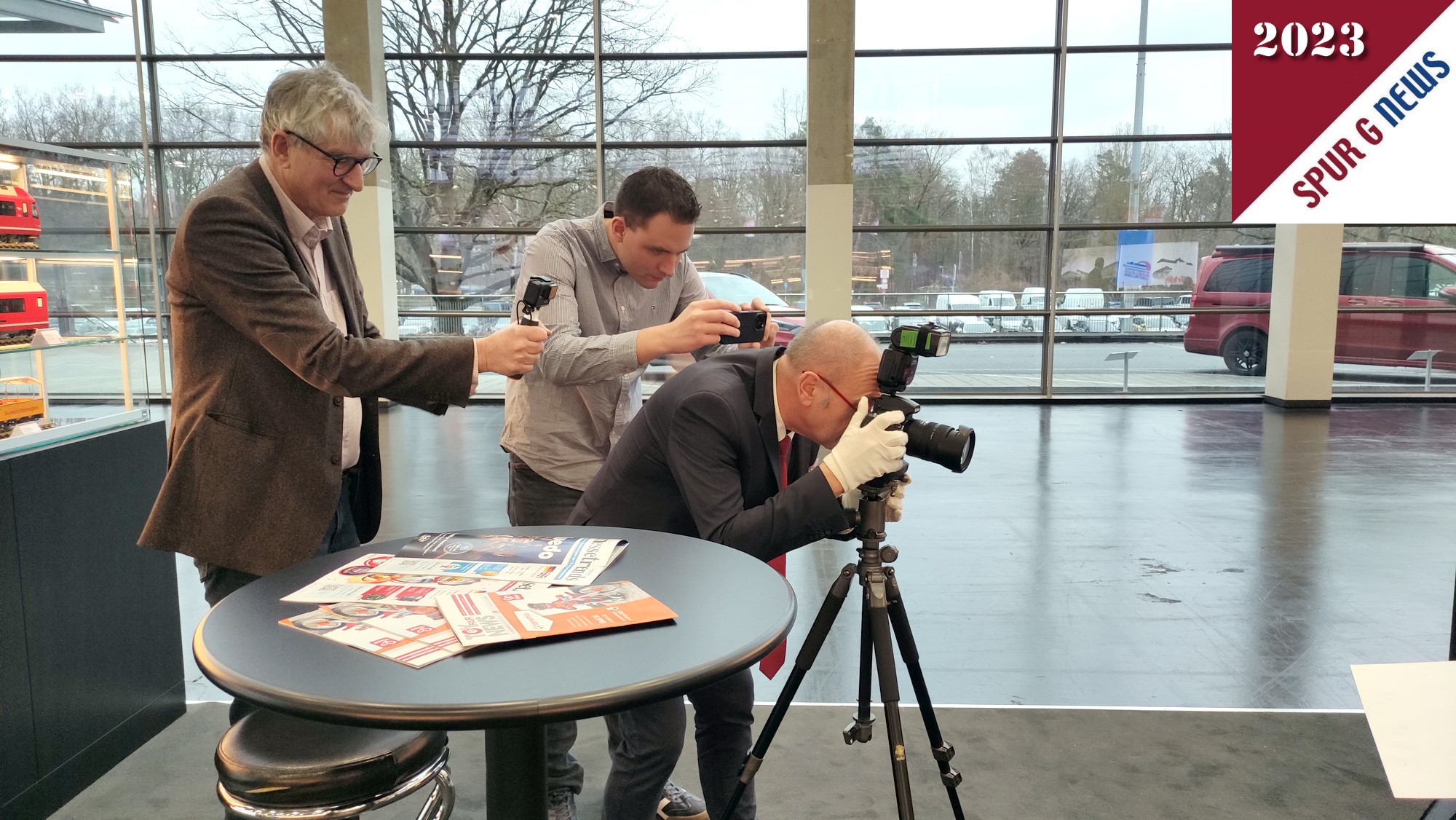 on links nach rechts: Markenbotschafter LGB Andreas Franz, Markenbotschafter von LGB Hendrik Hauschild und hinter der Kamera Spur G Magazin - Spur G News Stefan Khnlein. Bild vom Fotoshooting der Modell. So entstehen Aufnahmen. Was wir in 2024, sollte es eine Spielwarenmesse mit Eisenbahnbeteiligung geben, besser machen: Der Boden bei LGB war nciht fr Lanzeitaufnahmen vorgesehen. Die Vibrationen von laufenden Gsten haben die Bilder bei Langzeitbelichtung leicht verwackeln lassen. 