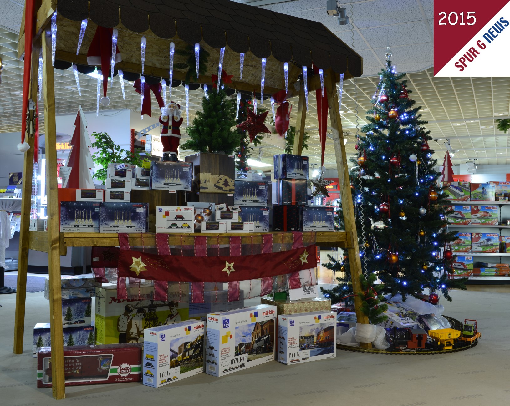 In der Erlebniswelt in Gppingen - angegliedert an das Mrklin Museum - steht dieser herrliche Marktstand und der mit Mrklin-Glaskugeln geschmckte Weihnachtsbaum. Hier wurde vom Leiter des Museums, Herrn Eugen Krey, auch an die LGB gedacht. Ein Zug aus der Anfangspackung wurde dekorativ mit einem Schienen Oval und den Geschenken um den Weihnachtsbaum gelegt. Der Heilige Abend kann kommen und bringt sicherlich den Modellbahnerinnen / Modellbahnern das Ersehnte. 