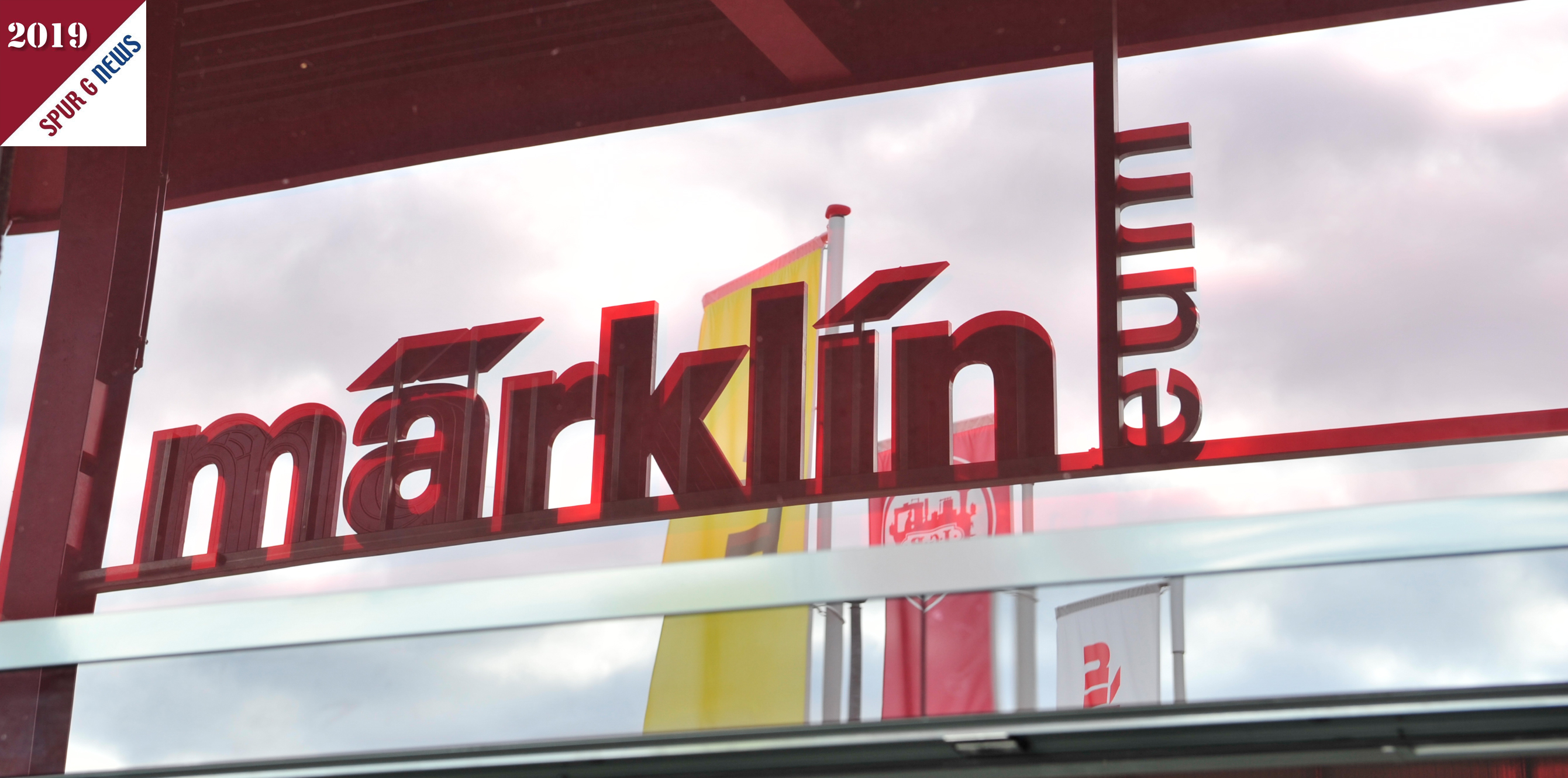 Im Glas der Eingangshalle spiegeln sich die Fahnen und der Schriftzug mit märklineum. Was war hier geboten? Kein Eintritt zu bezahlen und eine Werksführung am Freitag und Samstag. Die Fundgrube, auch hier bildete sich eine Menschenschlange, war diesmal in einem Zelt untergebracht. Auch die neue, im Bau befindliche, H0 Anlage konnte von oben besichtigt werden.