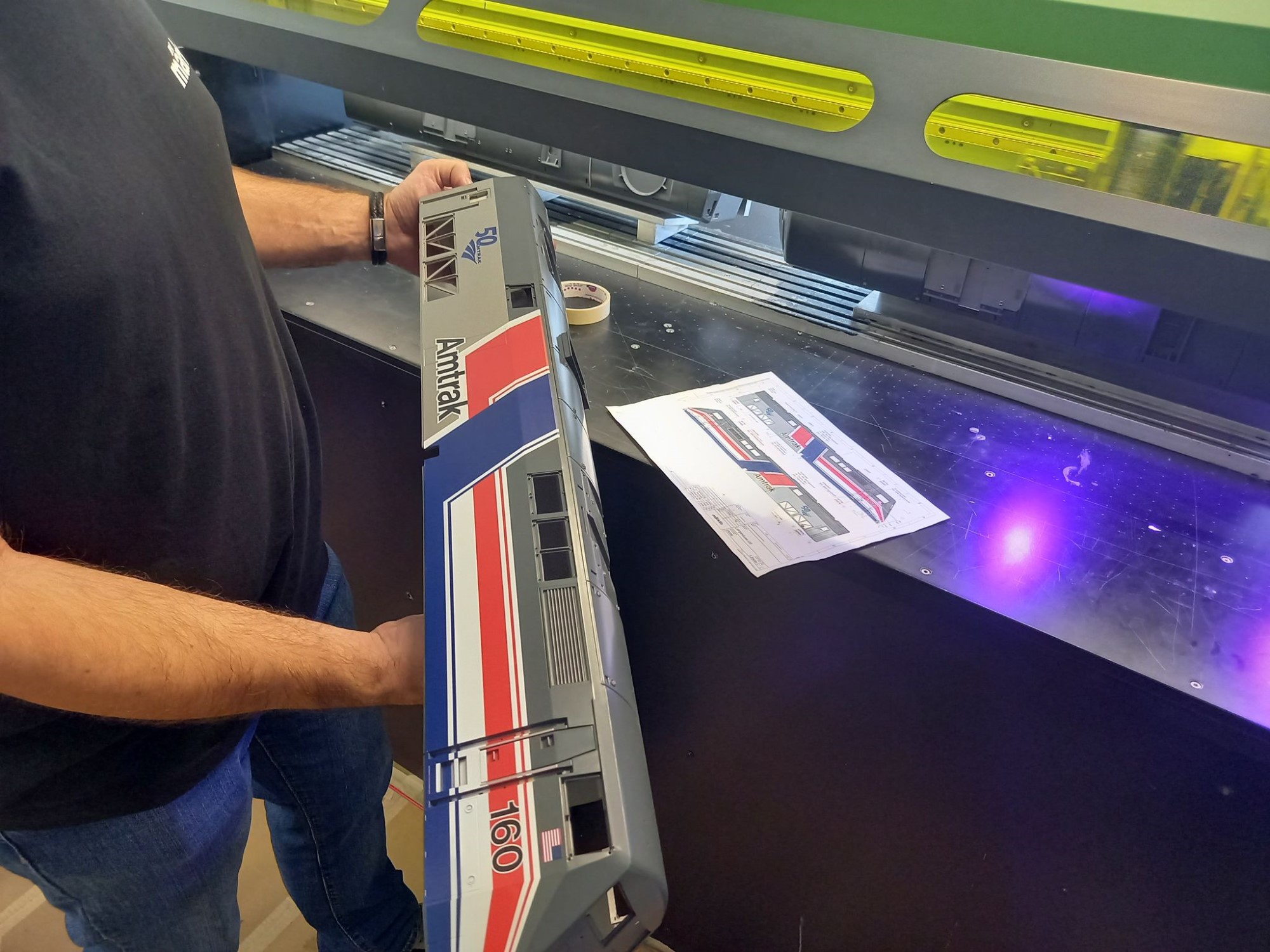 Kontrolle der seitlichen Bedruckung. Vergleich Vorlage und Original. Im Hintergrund der Drucker für diese langen Teile und den Digitaldruck.Ab Werk ausgerüstet mit US-Klauenkupplungen, LGB-Systemkupplungen liegen bei. Länge über Puffer 77 cm.