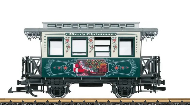LGB Artikel 36923, Weihnachtswagen 2023- USA, Christmas Passenger Car USA 2023, Das Motiv auf dem grünen Teil des Wagens sind die Hände des Weihnachtsmanns, mit Handschuhen, der gerade einen Wagen des Zuges sich näher betrachtet. Eine Stainz mit einem weiteren Wagen ist unter dem Weihnachtsbaum sichtbar