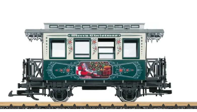 LGB Artikel 36923, Weihnachtswagen 2023- USA, Christmas Passenger Car USA 2023, Das Motiv auf dem grnen Teil des Wagens sind die Hnde des Weihnachtsmanns, mit Handschuhen, der gerade einen Wagen des Zuges sich nher betrachtet. Eine Stainz mit einem weiteren Wagen ist unter dem Weihnachtsbaum sichtbar