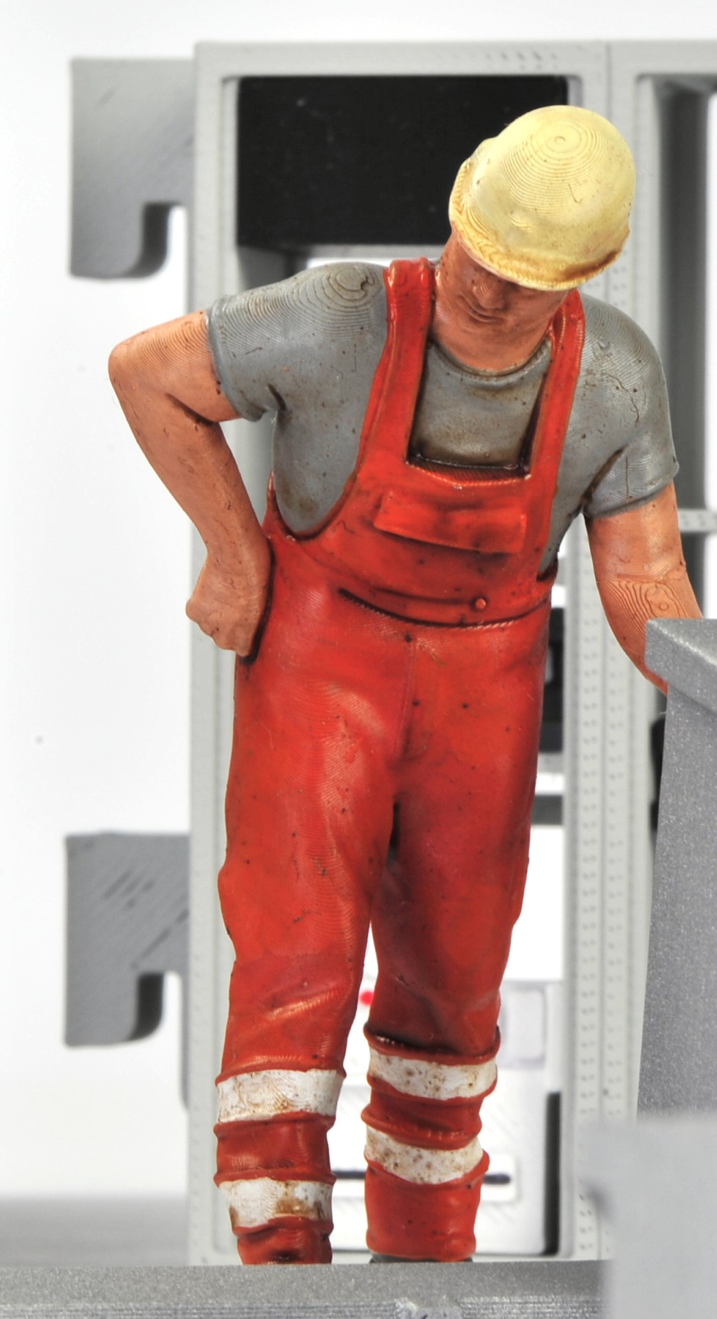 Der stehende RhB Bahnmitarbeiter mit dem gelben Schutzhelm, der Orangen Arbeitslatzhose und grauem Shirt ist für den Funkmesswagen von Volker Bauer figurendesign produziert worden.