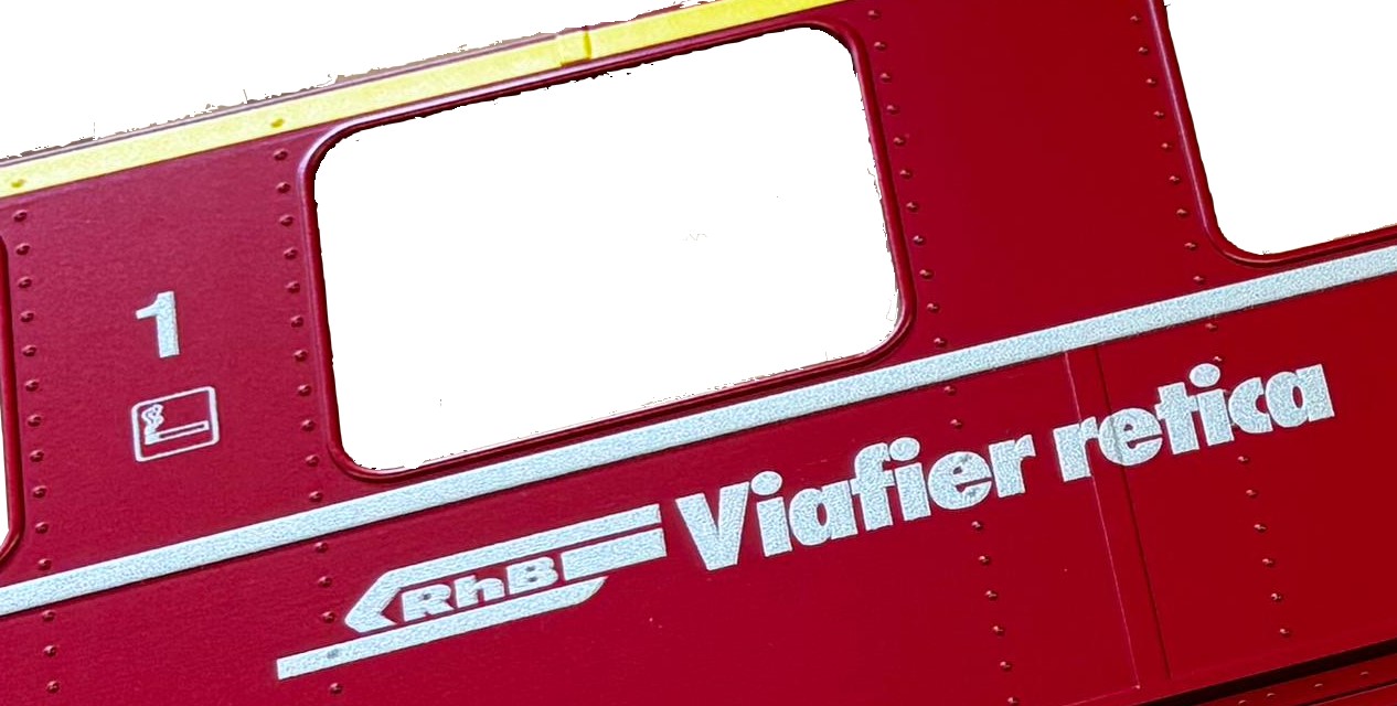 Bildausschnit: gelber 1. Klasse Streifen, Klasse 1 mit Raucher Piktogramm, Logo RhB und Viafier retica = Name der Rhtischen Bahn in rtoromaisch