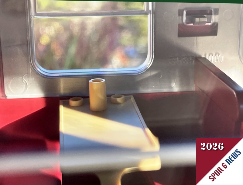 Blick durch das Fenster der SOEG Speisewagens LGB Art. Nr. 36364. Die B�nke sind in rotbraun gehalten und der Tisch mit den Becherhaltern und dem Lampeneinsatz (vielleicht ist es auch eine Blumenvase) ist in beiger Farbe gefertigt. 