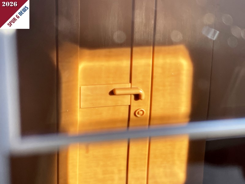 Ein besonderes Detail im Wageninneren ist die T�r zur Toilette. Hier ist die Holzmaserung sehr gut umgesetzt. Der Schatten verdeckt den oberen Teil der T�re. Sehr gut ausgebildet ist der T�rgriff und das Vierkantschloss. Hier wurde sogar an die Schutzabdeckung hinter dem Griff gedacht. Ein bisschen Farbe macht das Detail noch plastischer. Der Modellbahner kann dies ja nach seinen W�nschen gestalten. 