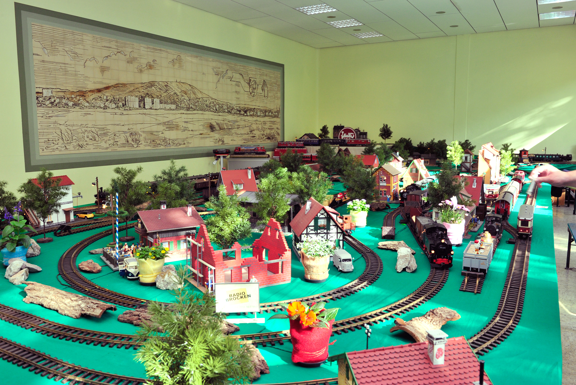 Die Gartenbahnstammtischler Thomas und Bernd, der Vorsitzende Dieter sowie alle weiteren "Anpacker" haben wieder eine tolle Anlage mit vielen Kreisen, Kreuzungen und Abstellmöglichkeiten geschaffen. Diesmal sind die grünen Tücher, Gleise, Gebäude und Ausschmückung auf standfesten Bühnengestellen aufgebaut. Kommen Sie die nächsten drei Tage vorbei uns sehen die Kunst der Gartenbahn von den Gartenbahnfreunden Grub a. Forst.