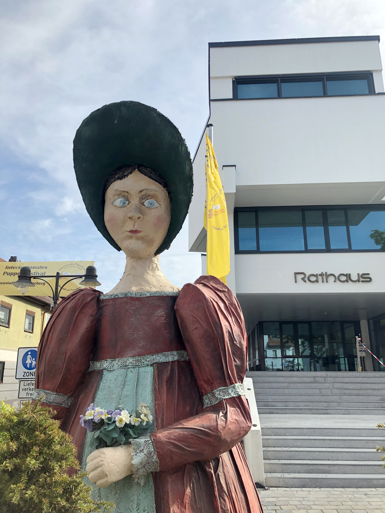 So ernst wie die Dame guckt und etwas schräg schaut ist die übergroße Puppe vor dem Rathaus in Neustadt bei Coburg nicht. Eben Kunst - vor dem Rathaus. (Bild links)