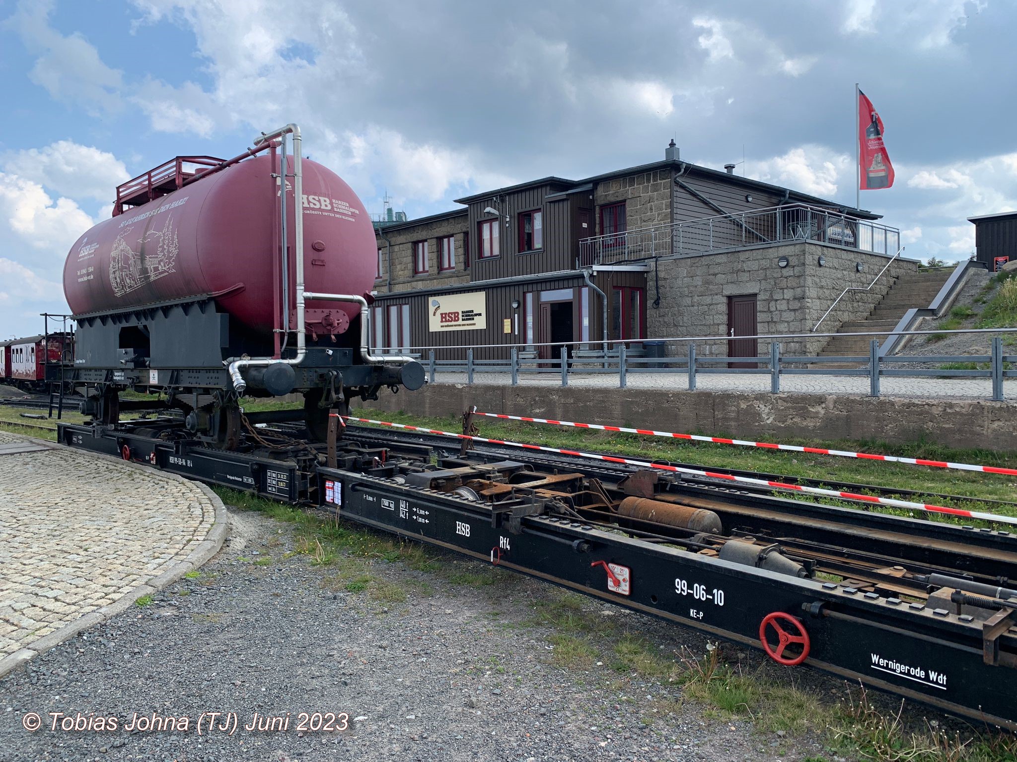 Die beiden Rollwagen der HSB vorne mit dem HSB Lschwasserwagen beladen: 99-50-54 und ohne Beladung 99-06-10. Blick zum Bahnhof Brocken in dem auch die Gaststtte untergebracht ist. 