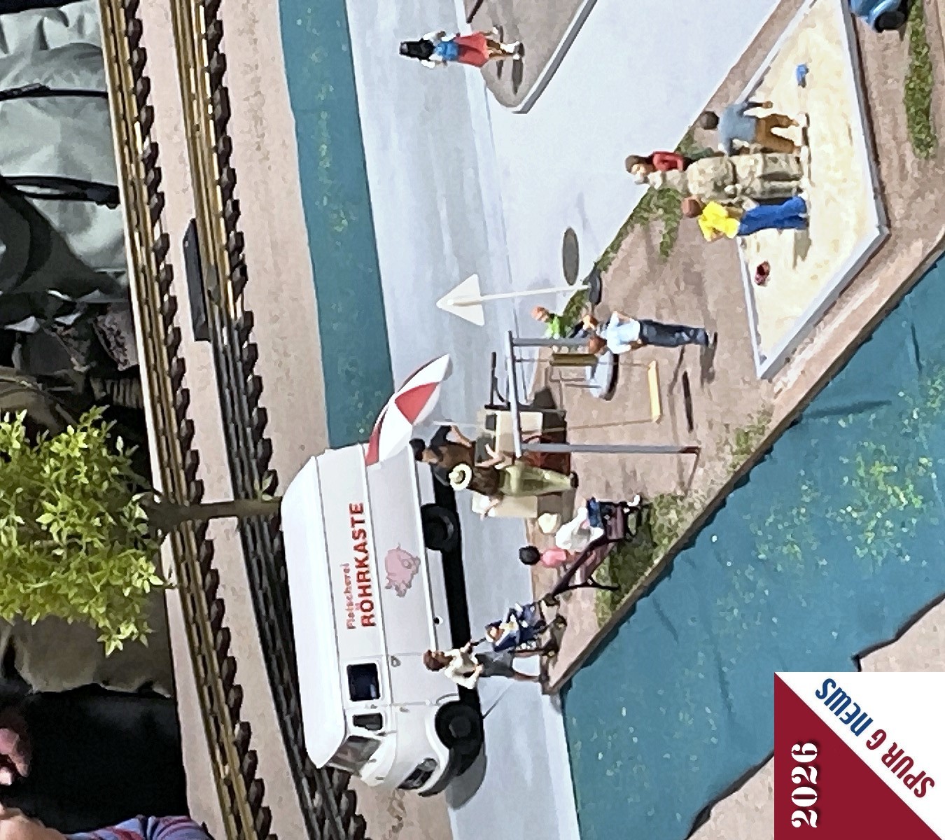 Die Detailliebe wurde mit der Aufschrift auf dem Kastenwagen und dem Spielplatz zwischen Stra�e (rechts) und dem angedeuteten Gr�nstreifen (links) gezeigt. Im Sandkasten wurde eine Kirche von den Kindern erbaut und die Mutter holt vom Eiswagen eine Erfrischung f�r die Kinder. 