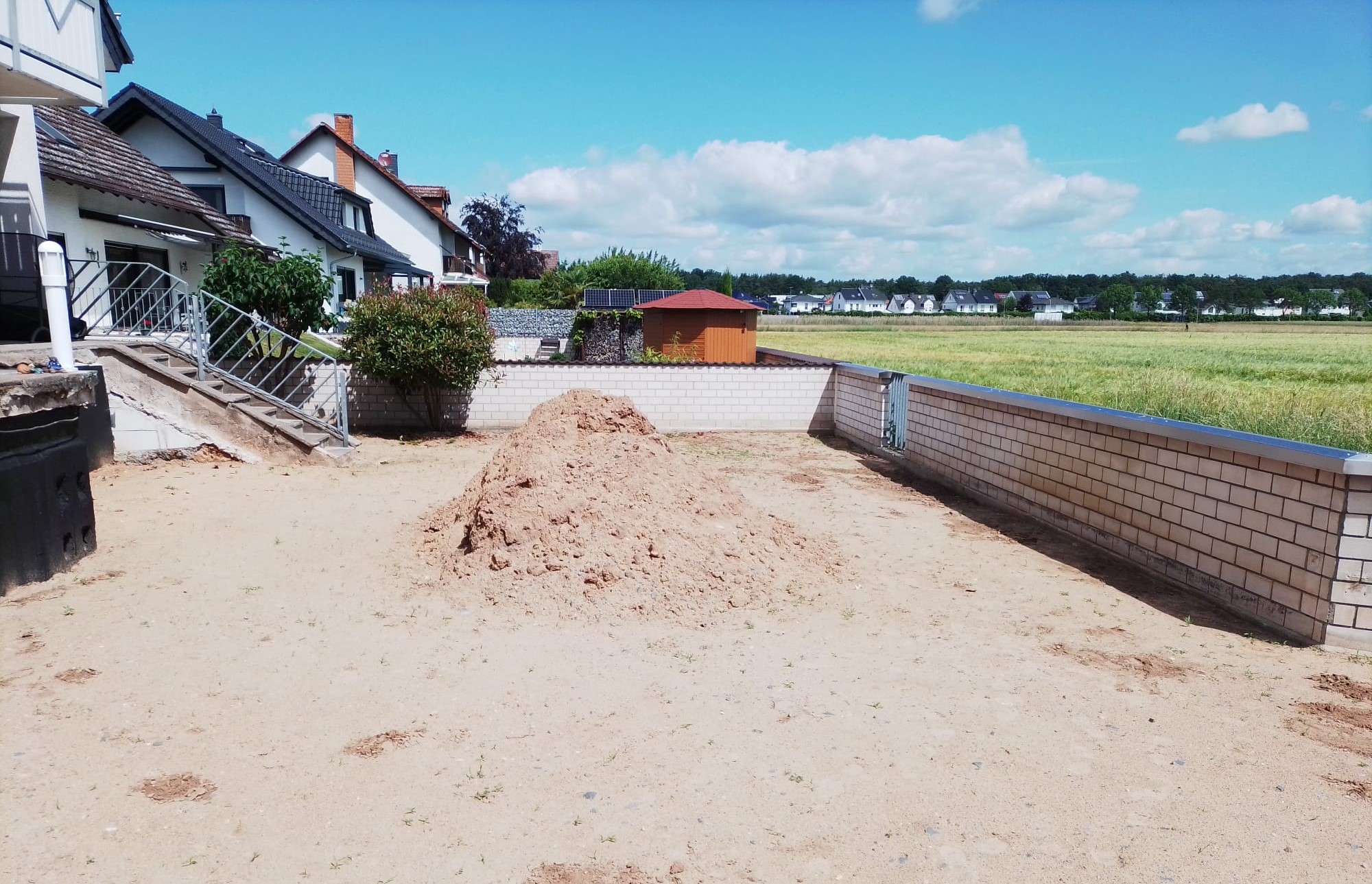 Der Garten vom Grün befreit. Links ist die Treppe zum Haus erkennbar. So "steil" war der Hang in den Garten. Am langen Teil der Außenmauer kommt nun der Bahnhof hin. Soviel sei schon vorab gesagt: Auf der Anlage kann, durch Austausch des Bahnhofsgebäudes mit RhB, Harz und USA gefahren werden.