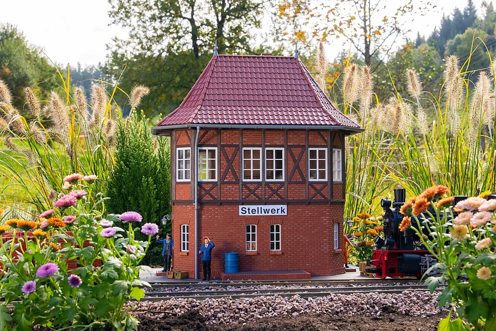 POLA Art. Nr. 330883 - Stellwerk mit Fachwerk - Dieses Stellwerk ist eine Nachbildung im Stil des Historismus, wie er f�r die eindrucksvollen Eisenbahnbauten des sp�ten 19. und fr�hen 20. Jahrhunderts typisch war. Die Kombination aus robustem Backsteinmauerwerk im Erdgeschoss und dekorativem Fachwerk im Obergeschoss verleiht dem Geb�ude seinen unverwechselbaren Charakter. Das markante, spitz zulaufende Mansardendach mit Fu�walm und filigranen Dachspitzen 