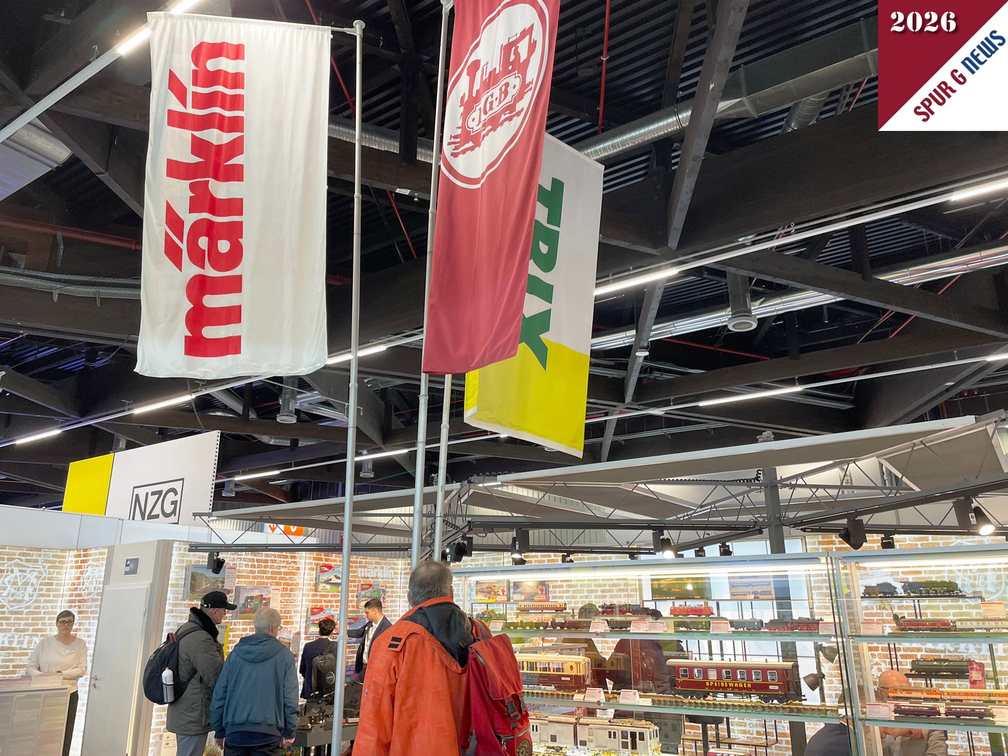 Zum 75. Jubiläum der Spielwarenmesse prästentiert sich Märklin, Trix und LGB auf 75qm Ausstellungsfläche. Von den LGB Neuheiten sind drei ausgestellt. Nachstehendes Foto zeigt den aufgelockerten Stand mit den Glasvitrinen und den obligatorischen Fahnen zur Erkennung der Marken.